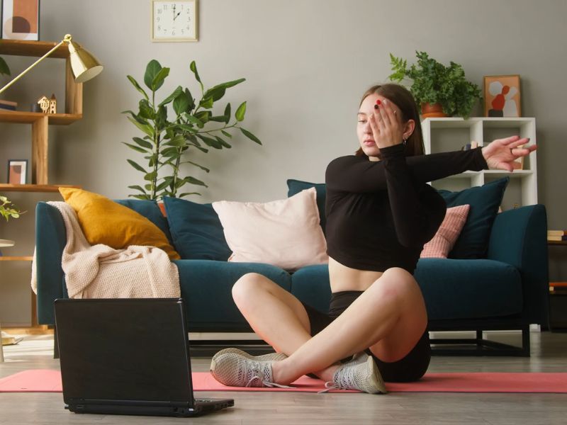 devojka trenira kod kuće gledajući tutorijal na laptopu